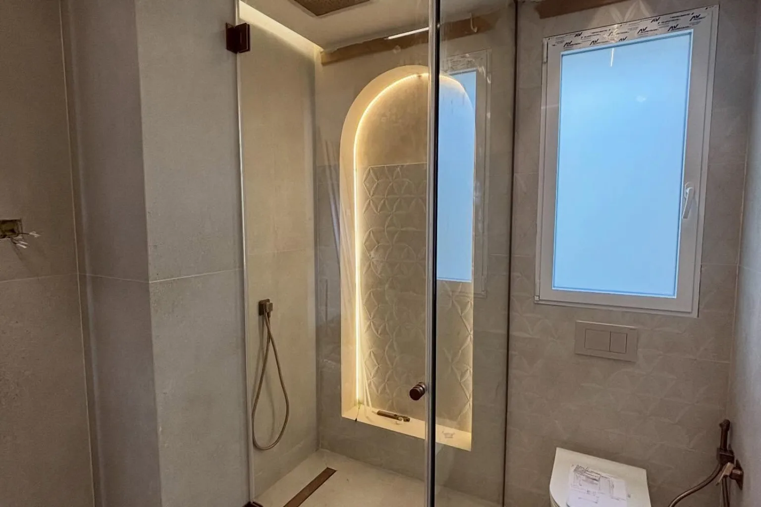 Mampara de ducha a medida de cristal templado de 10 mm con bisagras y perfilería en oro rosa, instalada por RM Cristalería
