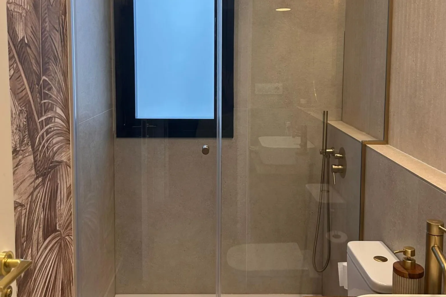 Mampara de ducha a medida de cristal templado con perfilería y bisagras en oro mate, instalada por RM Cristalería